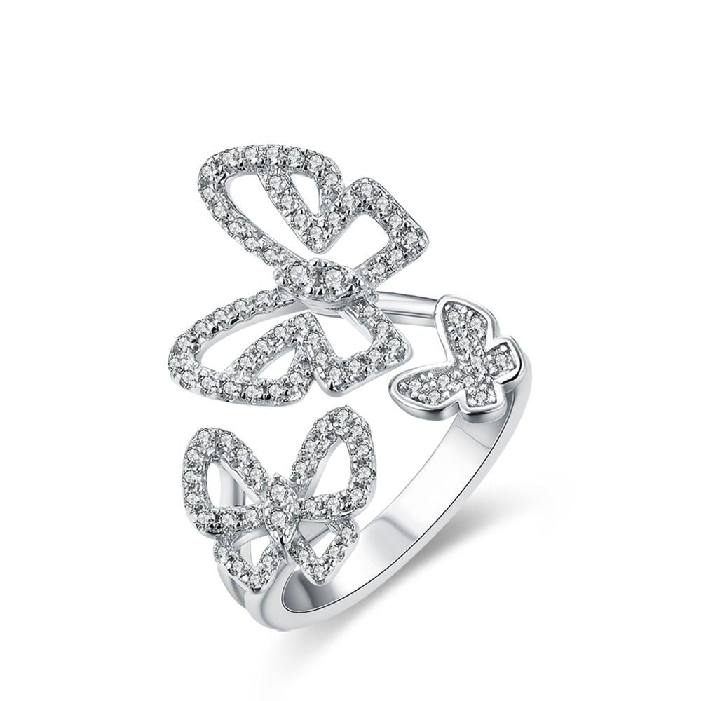 Sterling Silver Butterfly Ring
Moissanite butterfly ring in solid 925 sterling silver featuring three sparkling butterflies, displayed on a white background.
Close-up of triple butterfly moissanite ring on finger, sparkling brilliantly in natural light.
925 sterling silver butterfly ring worn by model in sheer long-sleeve top, showcasing elegant and whimsical style.
Product shot of butterfly ring with brilliant-cut Moissanite stones and adjustable band design.